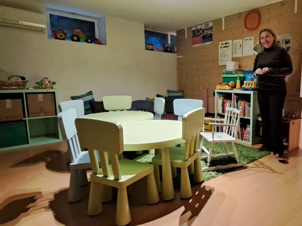 Spazio di Asilo di Sera dedicato ai bambini, con tavolino, sedie e libri.