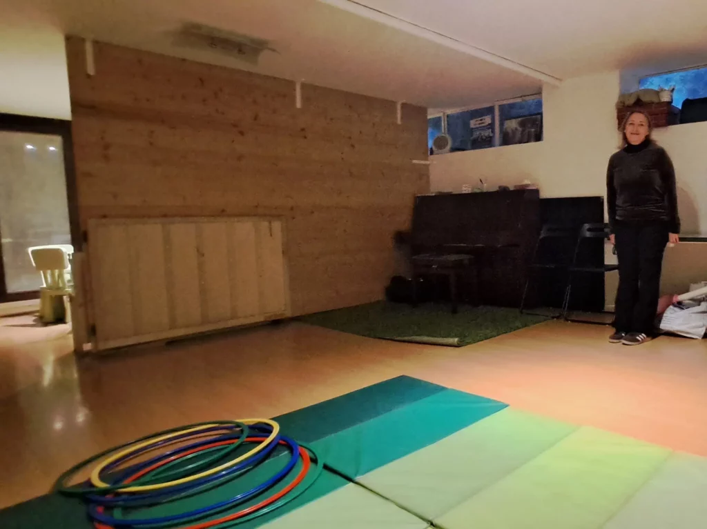 Sala giochi di Asilo di Sera con tappeti morbidi, cerchi colorati e pianoforte.