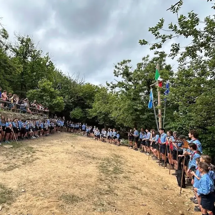 Scout riuniti in cerchio accanto alle bandiere nella base Le Casette.