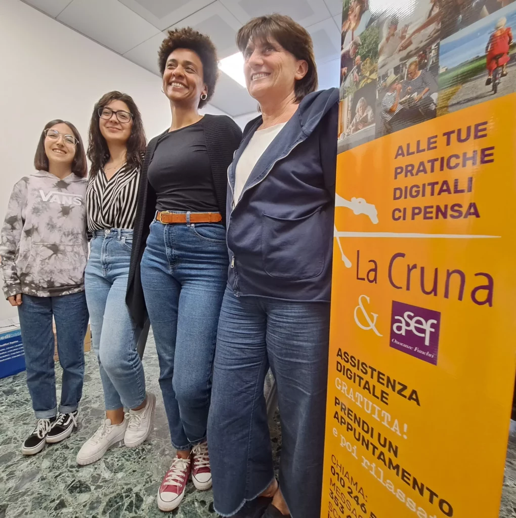 Staff della cooperativa La Cruna accanto al manifesto del servizio gratuito di assistenza digitale sostenuto da A.Se.F.