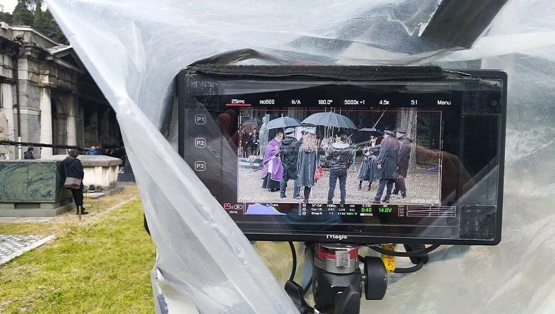 Monitor di ripresa con una scena funebre ambientata in un cimitero.