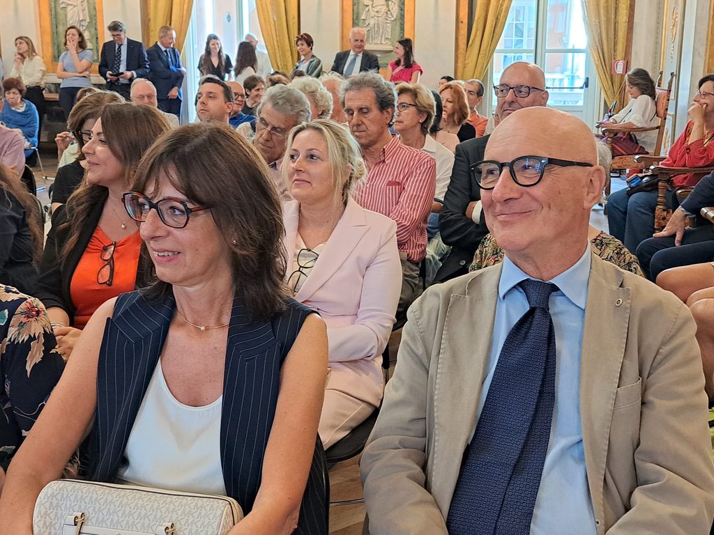 Due partecipanti in primo piano seguono la presentazione di Erbari Svelati a Palazzo Tursi.