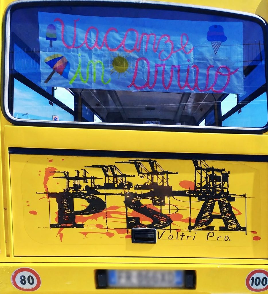 Vista posteriore dello scuolabus giallo, decorato con disegni e scritte colorate.
