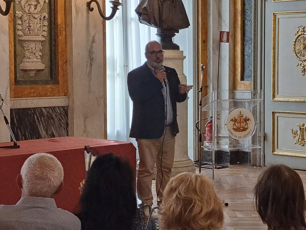 Un relatore interviene al microfono davanti al pubblico della conferenza.