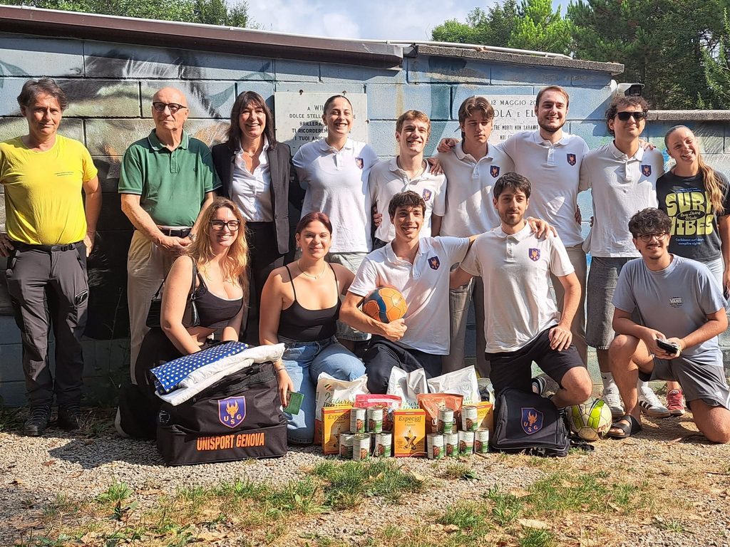 Il gruppo di Unisport Genova e i volontari del canile Montecontessa posano con coperte, cibo e palloni raccolti per i cani.